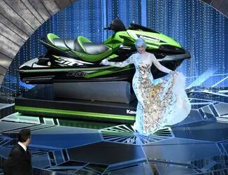 هلن میرن مقابل جت‌اسکی ایستاده و جیمی کیمل او را تماشا می‌کند. این جت‌اسکی جایزه برنده‌ای بود که کمتر از همه حرف بزند